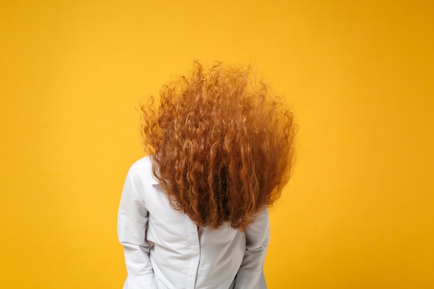 Crazy young redhead woman girl in casual white shirt posing isolated on yellow orange wall