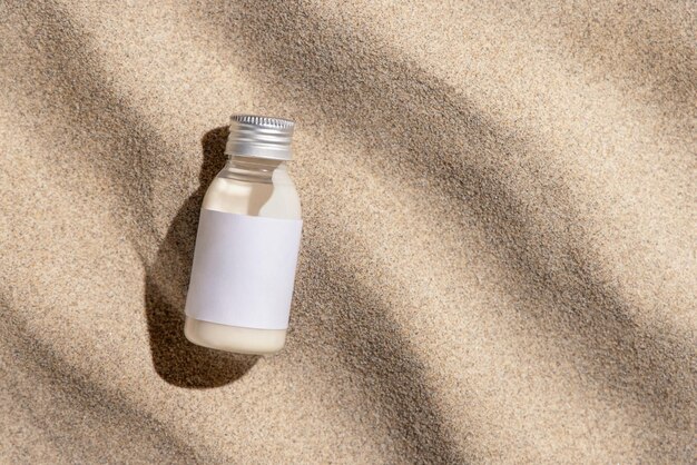 Cream bottle with blank label on beige sand top view hard light Cosmetic packaging mockup