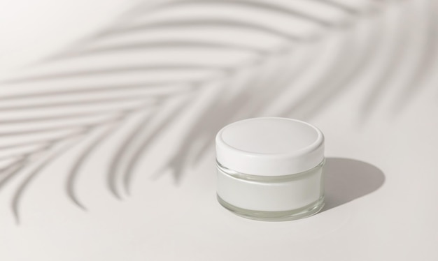 Cream jar with a blank white lid on white close up Palm leaf hard shadow Cosmetic Mockup