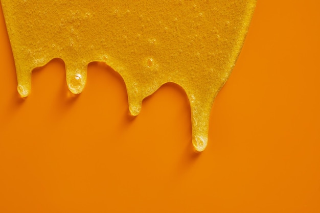 Cream liquid gel serum flowing down on yellow texture