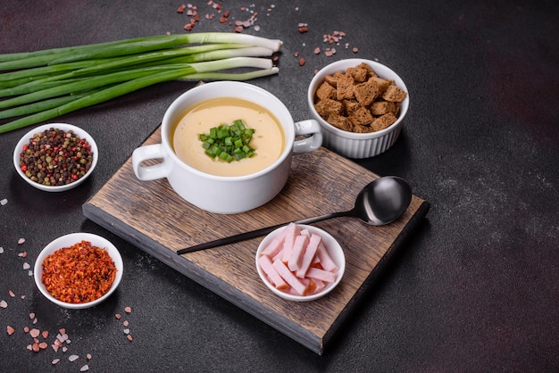 Cream soup with potatoes leek and peas on a dark concrete table