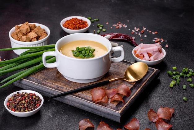 Cream soup with potatoes leek and peas on a dark concrete table