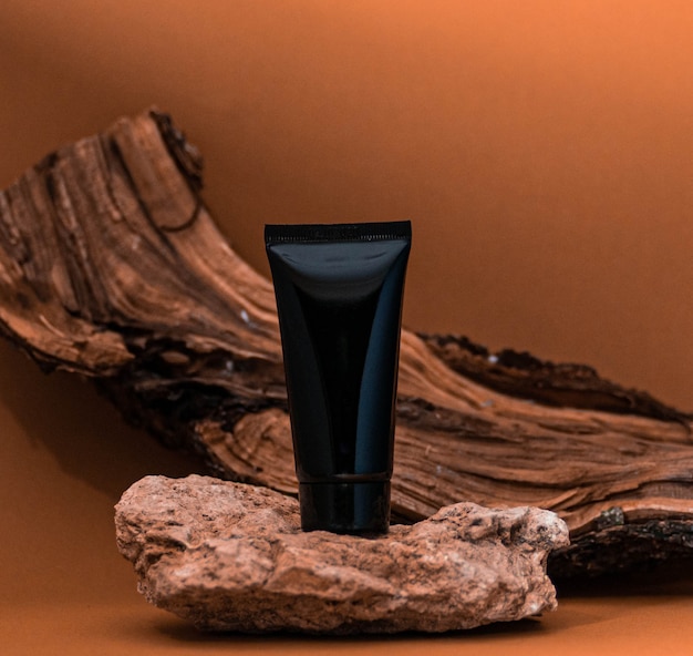 The cream tube stands on a light stone with a background of wood. Natural concept. Ð¡ream tube on a natural background.