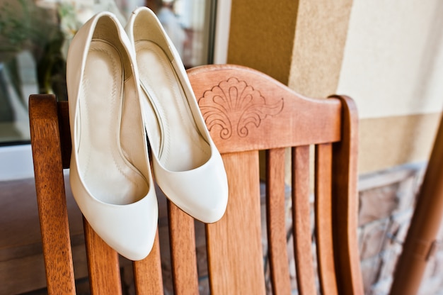 Cream wedding shoes of bride on wooden chair