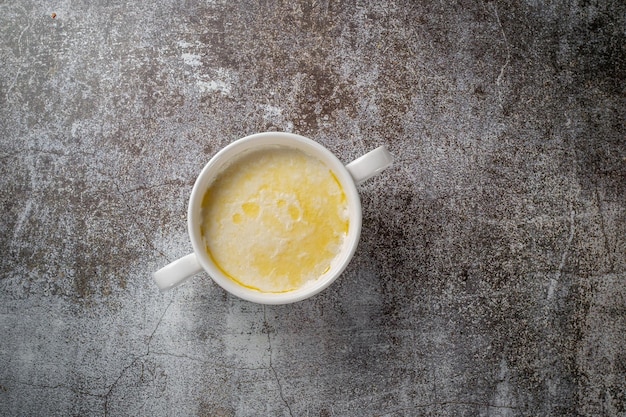 Cream of wheat, semolina pudding with butter in a white cup against a gray stone table. A healthy breakfast in a restaurant