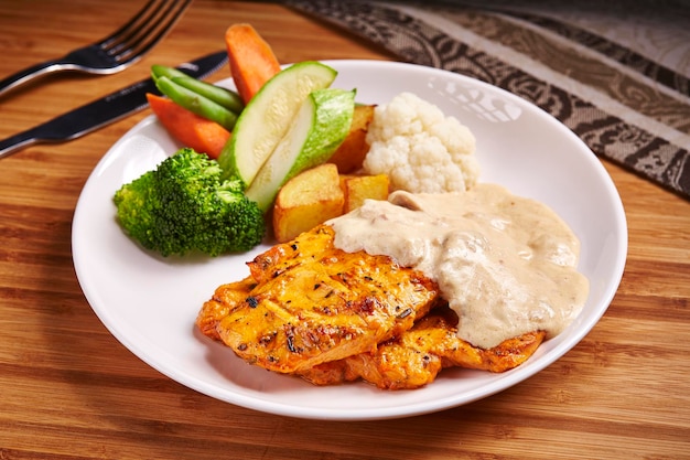 Creamy Grilled Chicken Breast with salad tomato cucumber and potato served in dish isolated on table side view of middle east food