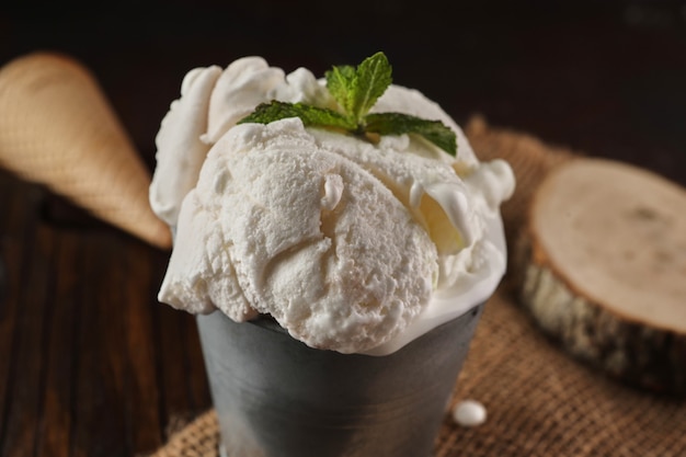 Creamy ice cream in bucket on wooden background and burlap in rustic style. Close up