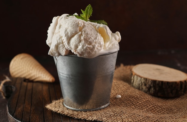 Creamy ice cream in bucket on wooden background and burlap in rustic style.