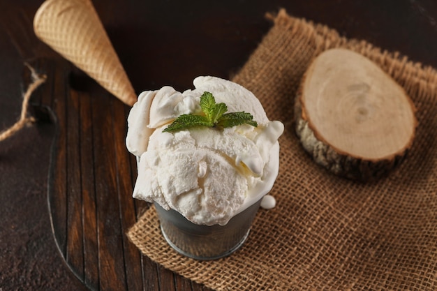 Creamy ice cream in bucket on wooden background and burlap in rustic style.