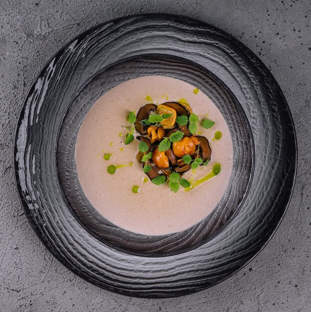 Creamy mushroom soup with champignons on stone background