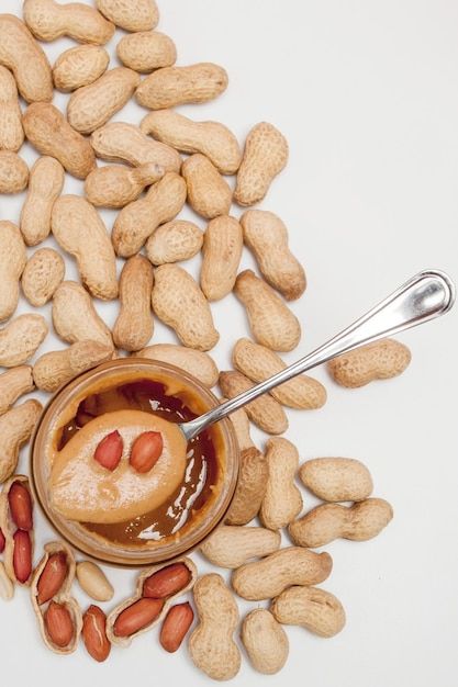 Creamy peanut butter in glass jar peanut and spoon isolated on white background A traditional product of American cuisine