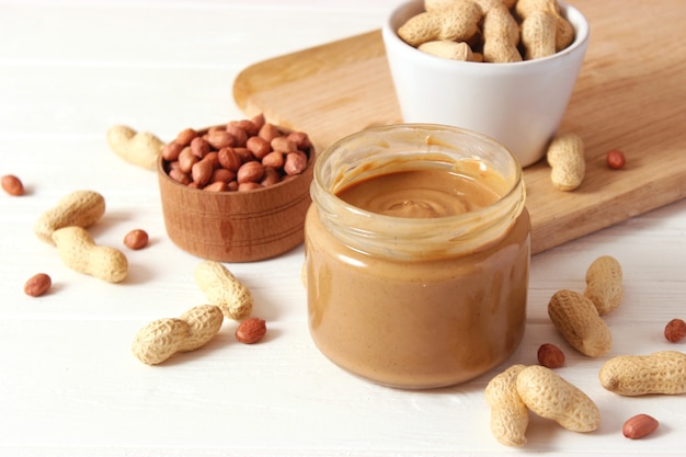 Creamy peanut butter and peanuts beans on wooden background top view. High quality photo