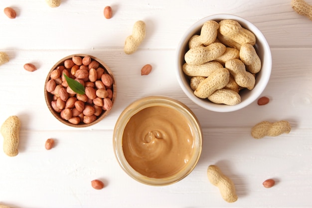 Creamy peanut butter and peanuts beans on wooden background top view