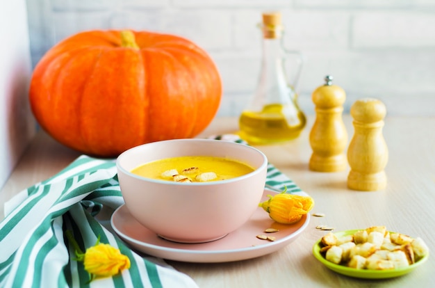 Creamy pumpkin soup with seeds and croutons in a bowl.