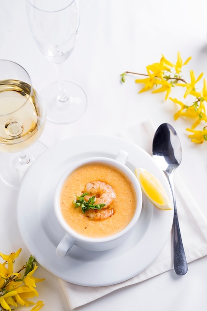 Creamy soup with seafood and lemon on a white background.