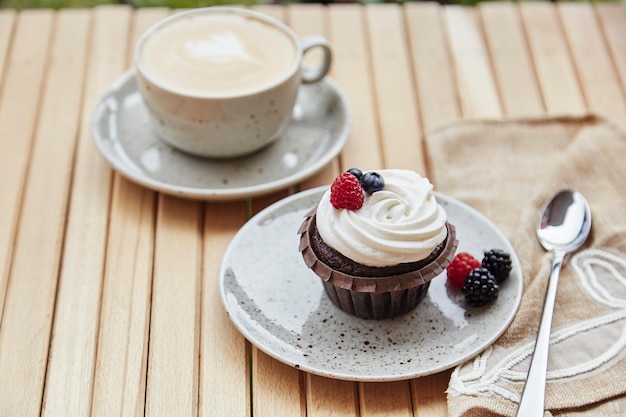 Creamy tender berries cupcake with cup of cappuccino outside Atmospheric cozy lunch at the terrace