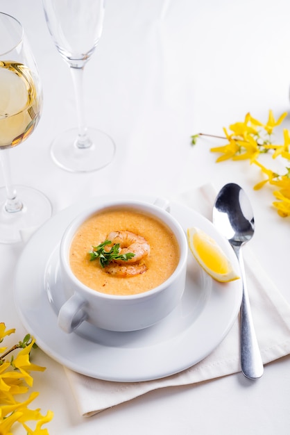 Creamy tomato soup with seafood and lemon on a white background.