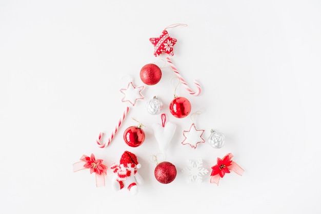 Creative arrangement of bright red christmas tree made of christmas ball, sweets, toys on white background.