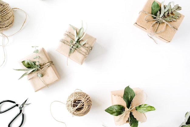 Creative arrangement pattern of craft boxes and green branches on white background.