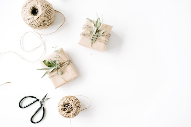 Creative arrangement pattern of craft boxes and green branches on white background.