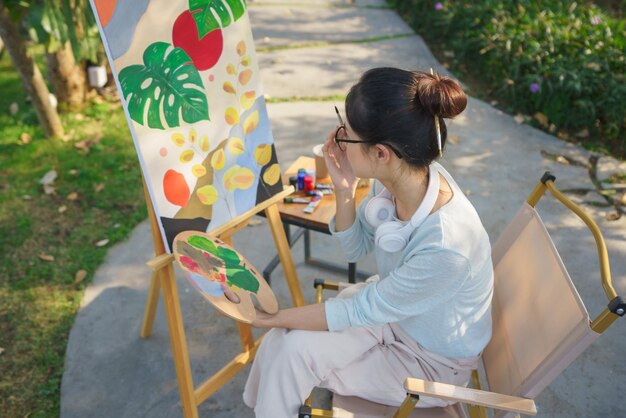 Creative art concept Female artist thoughtful while looking on painting art in canvas at garden