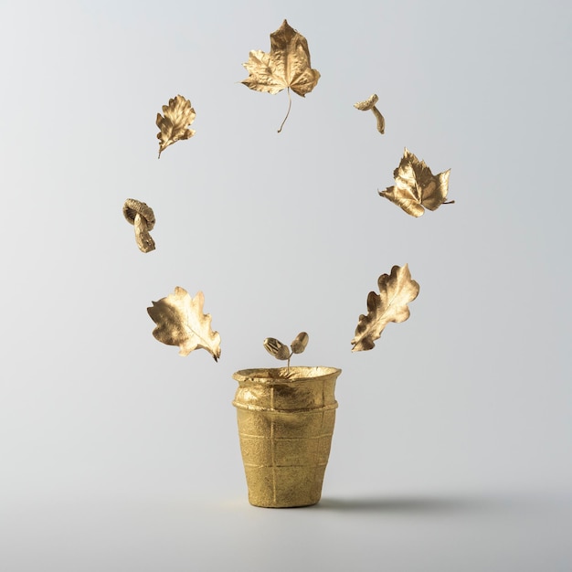 Creative autumn layout of gold leaves flying out of a wafer cup on a gray background