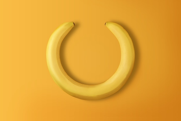 Creative banana wreath on yellow background with copy space. Top view.