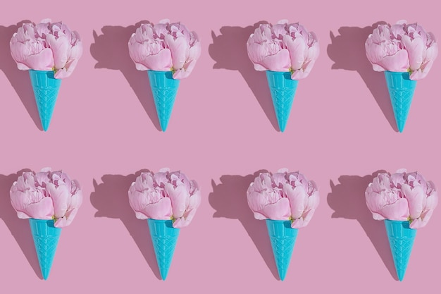 Creative blue toy ice cream cone with pink peony fluffy flower on pink minimal background with copy space flat lay Botany idea for summer or spring wallpaper or greeting card Seamless pattern