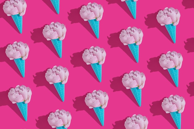 Creative blue toy ice cream cone with pink peony fluffy flower on pink minimal background with copy space flat lay Botany idea for summer or spring wallpaper or greeting card Seamless pattern