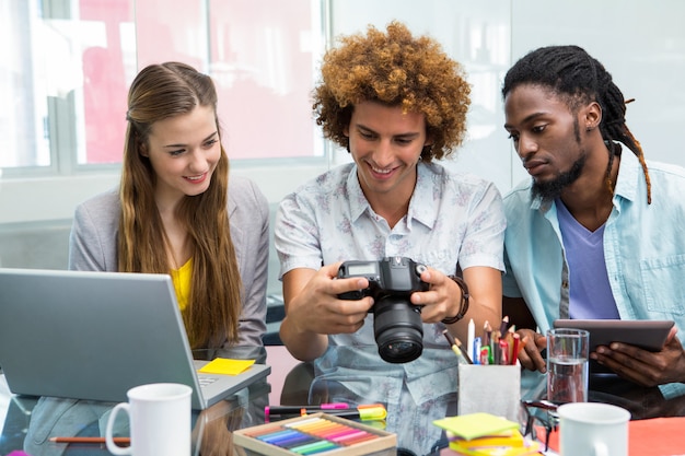 Creative business people looking at digital camera at desk