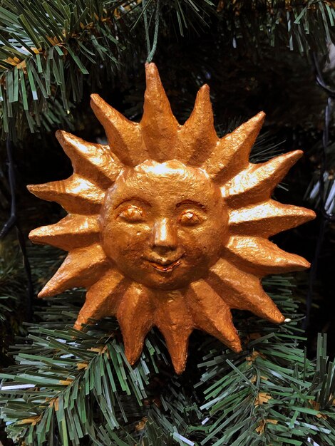 Creative Christmas decor Sun figure on Christmas tree. New Year celebration, winter holiday mood