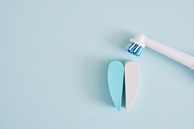 Creative composition of electric toothbrush and teeth on a blue background which brushes are more effective in cleaning the oral cavity and more ecofriendly