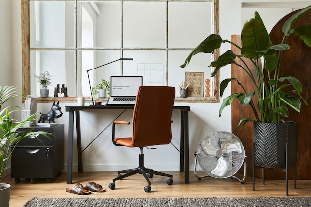 Photo creative composition of modern masculine home office interior design with black industrial desk, brown leather armchair, laptop and stylish personal accessories. template.