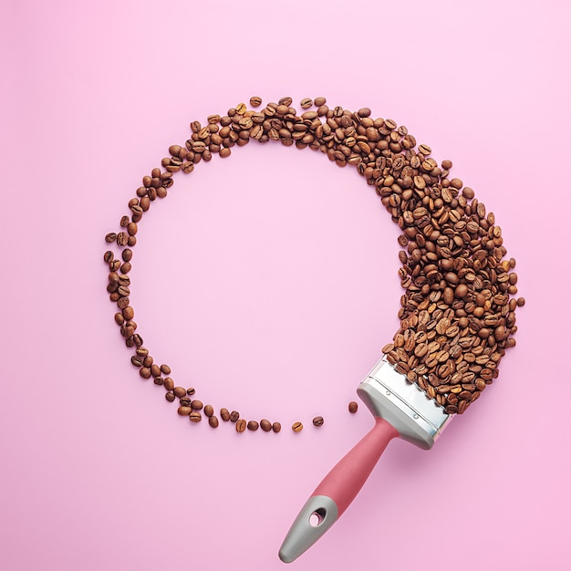 Creative composition of a wreath of coffee beans on a pink background with copy space. Top view.