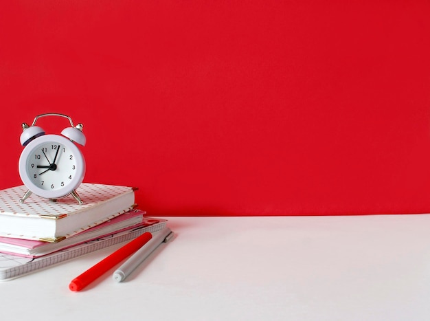 Creative desk with notebook desk objects office supplies books on white table red wall Student's desk Creative workspace front view Mock up