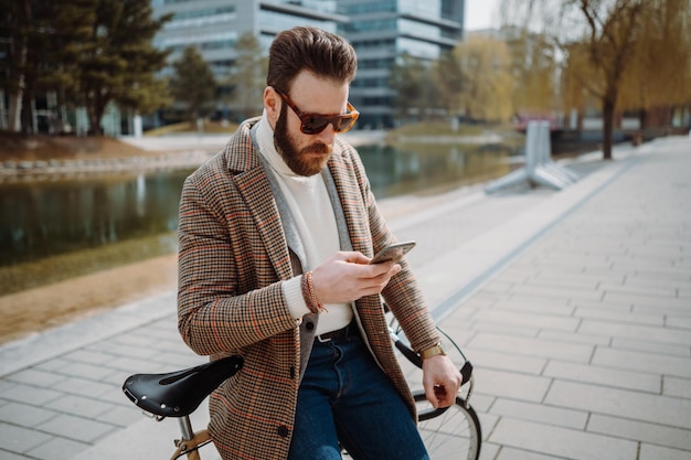 Creative director using mobile phone man standing next to bicycle with smartphone high quality photo