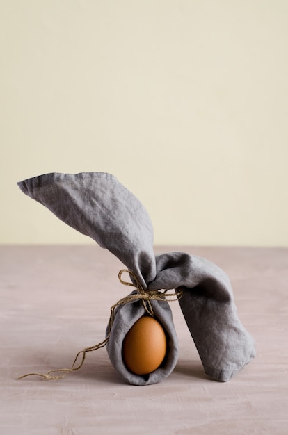 Creative Easter bunny, chicken egg is wrapped in a gray napkin