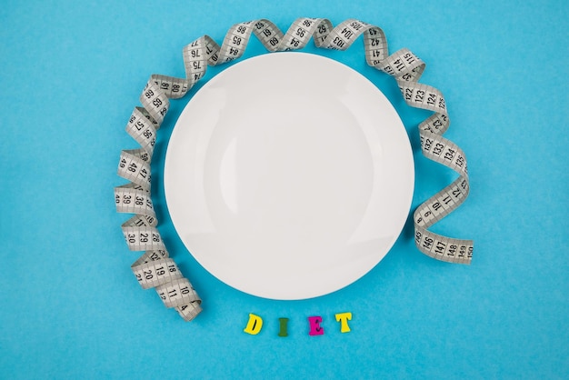 Creative flat lay composition with plate and measuring tape on dewy background Intermittent fasting ketogenic diet concept flat lay