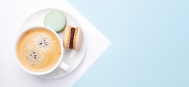 Creative flat lay. Cup of coffee, various macarons on blue background. Long horizontal banner - Image