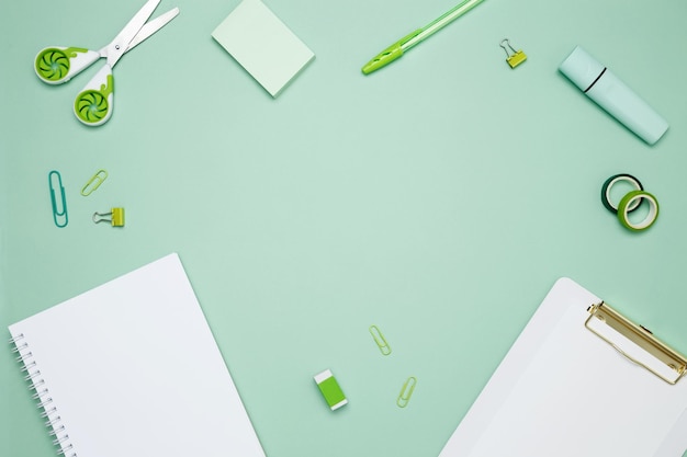 Photo creative flat lay mockup design of workspace top view composition with white notebook to do list and stationery on green background