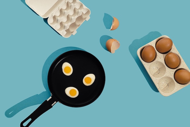 Creative food concept with gummy candy fried egg shaped with egg shell in a black frying pan over blue background Morning breakfast top view Seamless pattern minimal style Flat lay