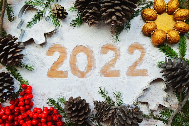 Creative greeting card Happy New Year 2022 Flour figures on a wooden background and green branches