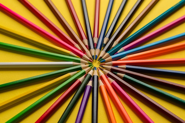 A creative idea of colorful crayons making a circle shape on the pastel background