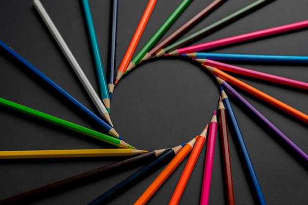 A creative idea of colorful crayons making a circle shape on the pastel background