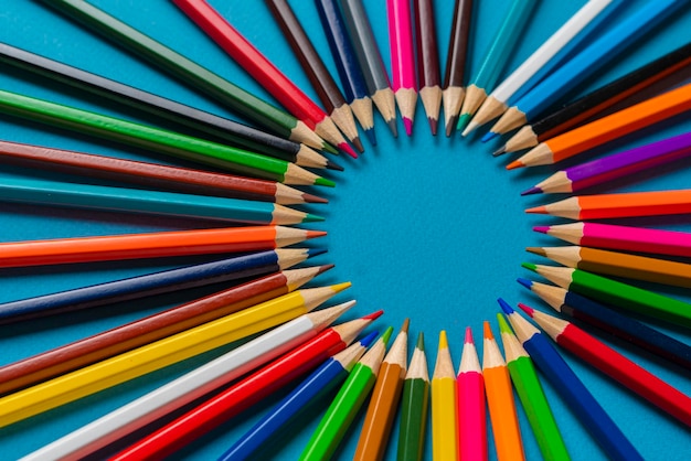 A creative idea of colorful crayons making a circle shape on the pastel background