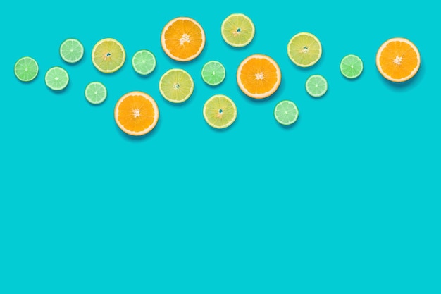 Creative layout made of colorful tropical fruits isolated on blue background Minimal summer concept Citrus fruit pattern Pop art flat lay top view Orange Lime Lemon slices background Copy space