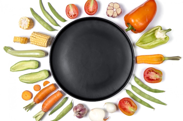 Creative layout made of haricot, tomatoes, pepper, carrot, garlic, corn, zucchini, onion and black plate. 