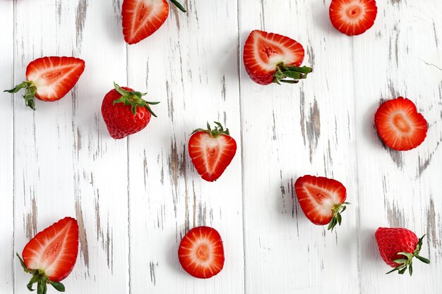 Creative layout of strawberries on the white wooden background