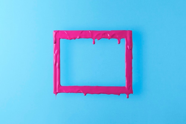 Creative layout with a pink melting frame Rectangular pink frame with paint drips on a blue background