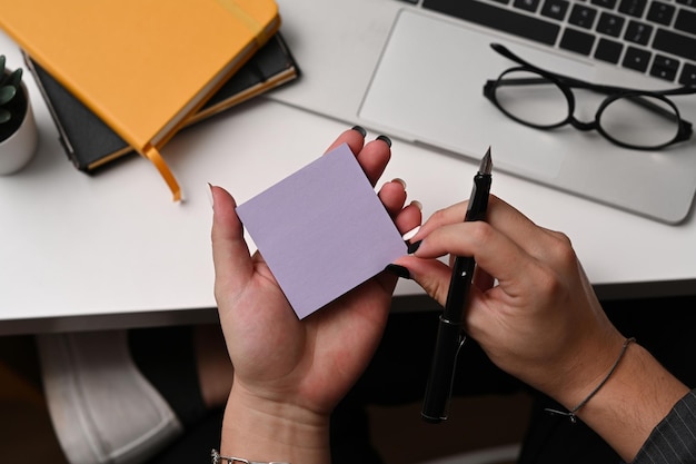 Photo creative man hand holding pen and sticky note close up view